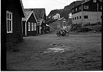 CW1929.   Ørnes gamle handelssted  1948 - 1950.<br>Mellom meieriet og kaibygningene kan vi se &quotNattkafeen&quotmed venterom .  Mannen på motorsykkelen er gjenkjent som Odd Kristensen, Eidbukt, ved siden står Arne Pedersen, Barvik.<br><br>