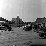 CW2752.jpg     Konfirmasjonssøndag: Dette bildet er sansynligvis tatt i 1955. Bilen foran det gamle posthuset, er en 1955-mod De Soto Diplomat (tilhørte Lindor O. Mosvold), og trolig den samme som er fremst på bildet av fem drosjer langs veien i Våtvik. Bilen foran bussene er Ingvar Storviks Hudson, fra 1949, som han byttet ut i 1955. Dette tyder på at bildet er tatt dette året. Bussene er fra v. den som Lars Ragnvaldsen kjørte; En Scania-Vabis fra 1947. Den neste er den såkalte Sulis-bussen, som Boldevin kjøpte brukt fra Sulitjelma i 1952, og som Reidar Johnsen kjørte realskoleelever med på 1950-tallet. Den mørke bilen midt på bildet, Drosje W-240, vet jeg ikke hvem som eide, men bilen kan identifiseres som en Ford Custom Fordor Sedan, 1951-modell.       OppLysn.: Jarle Elverhøy<br>