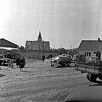 CW2752.jpg     Konfirmasjonssøndag: Dette bildet er sansynligvis tatt i 1955. Bilen foran det gamle posthuset, er en 1955-mod De Soto Diplomat (tilhørte Lindor O. Mosvold), og trolig den samme som er fremst på bildet av fem drosjer langs veien i Våtvik. Bilen foran bussene er Ingvar Storviks Hudson, fra 1949, som han byttet ut i 1955. Dette tyder på at bildet er tatt dette året. Bussene er fra v. den som Lars Ragnvaldsen kjørte; En Scania-Vabis fra 1947. Den neste er den såkalte Sulis-bussen, som Boldevin kjøpte brukt fra Sulitjelma i 1952, og som Reidar Johnsen kjørte realskoleelever med på 1950-tallet. Den mørke bilen midt på bildet, Drosje W-240, vet jeg ikke hvem som eide, men bilen kan identifiseres som en Ford Custom Fordor Sedan, 1951-modell.       OppLysn.: Jarle Elverhøy<br>